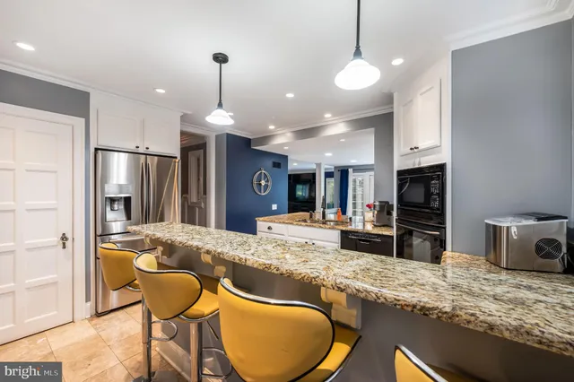 a kitchen with granite countertop kitchen island stainless steel appliances a sink stove and refrigerator