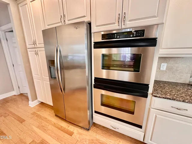 a dining room with wooden floor a chandelier a glass table and chairs