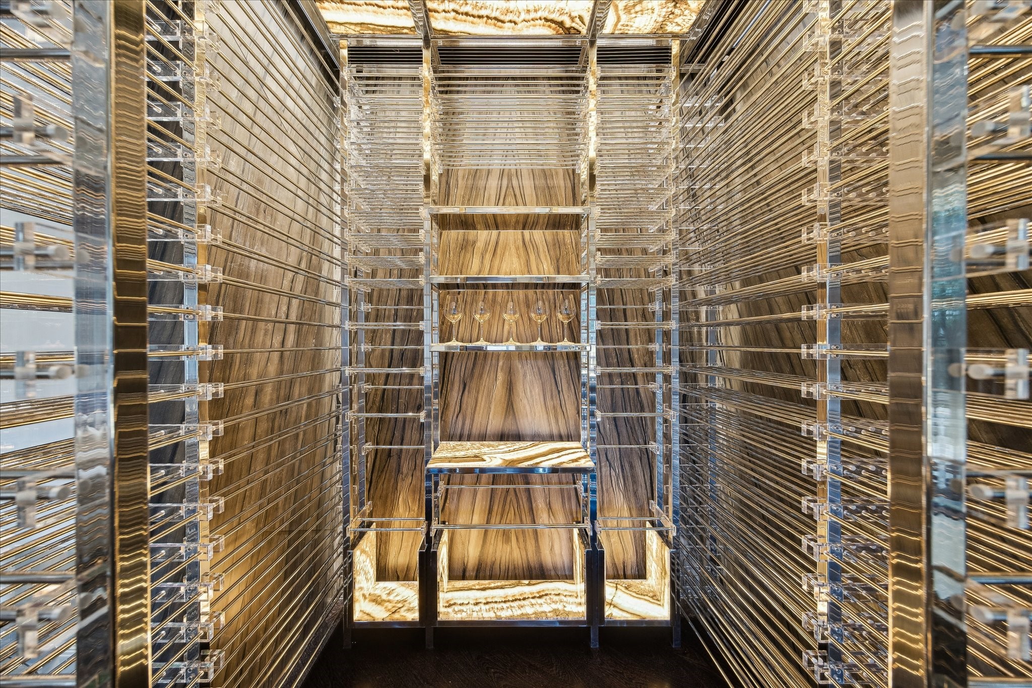 220 Merrie Way Lane Houston, TX 77024 - Photo 16 of 50 Designed by Ken Newberry, this fully custom wine room features a steel-and-glass enclosure, climate control, and double-layered steel racks with a 750+ bottle capacity. Herringbone oak floors and backlit onyx ceiling and accent walls create a dramatic, gallery-like setting for an impressive collection.