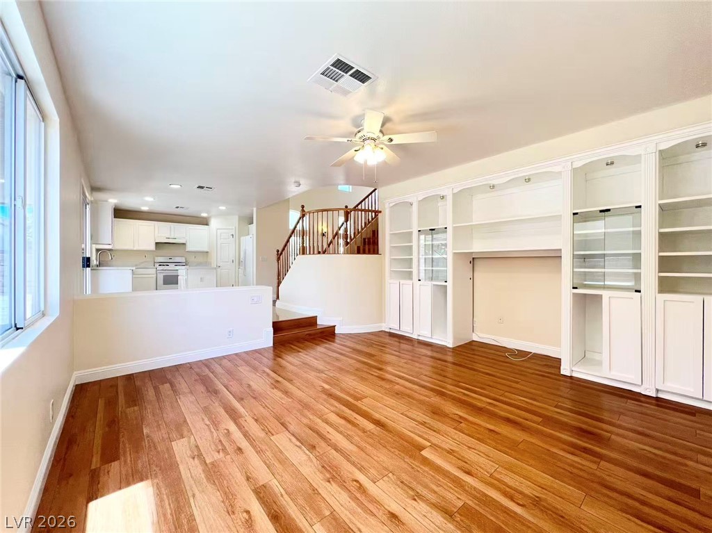 9891 Ridge Hill Avenue Las Vegas, NV 89147 - Photo 10 of 29 Natural light illuminates rich hardwood flooring and a functional built-in entertainment center.
