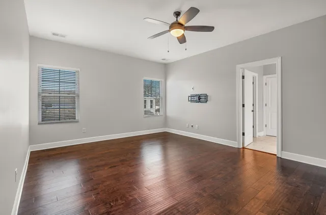 an empty room with wooden floor and ceiling fan