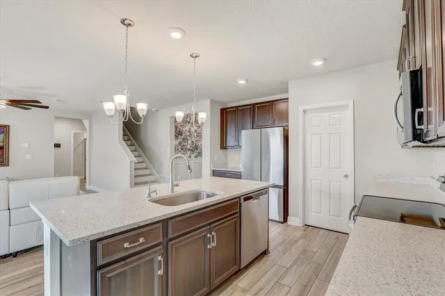 a view of a kitchen island a sink wooden floor and a chandelier