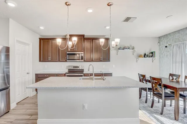 a kitchen with kitchen island granite countertop a table chairs sink and cabinets