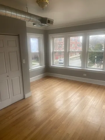 a view of an empty room with a window and wooden floor