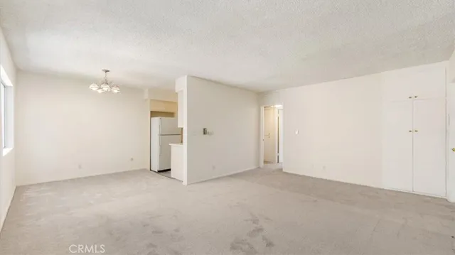 an empty room with chandelier fan and windows