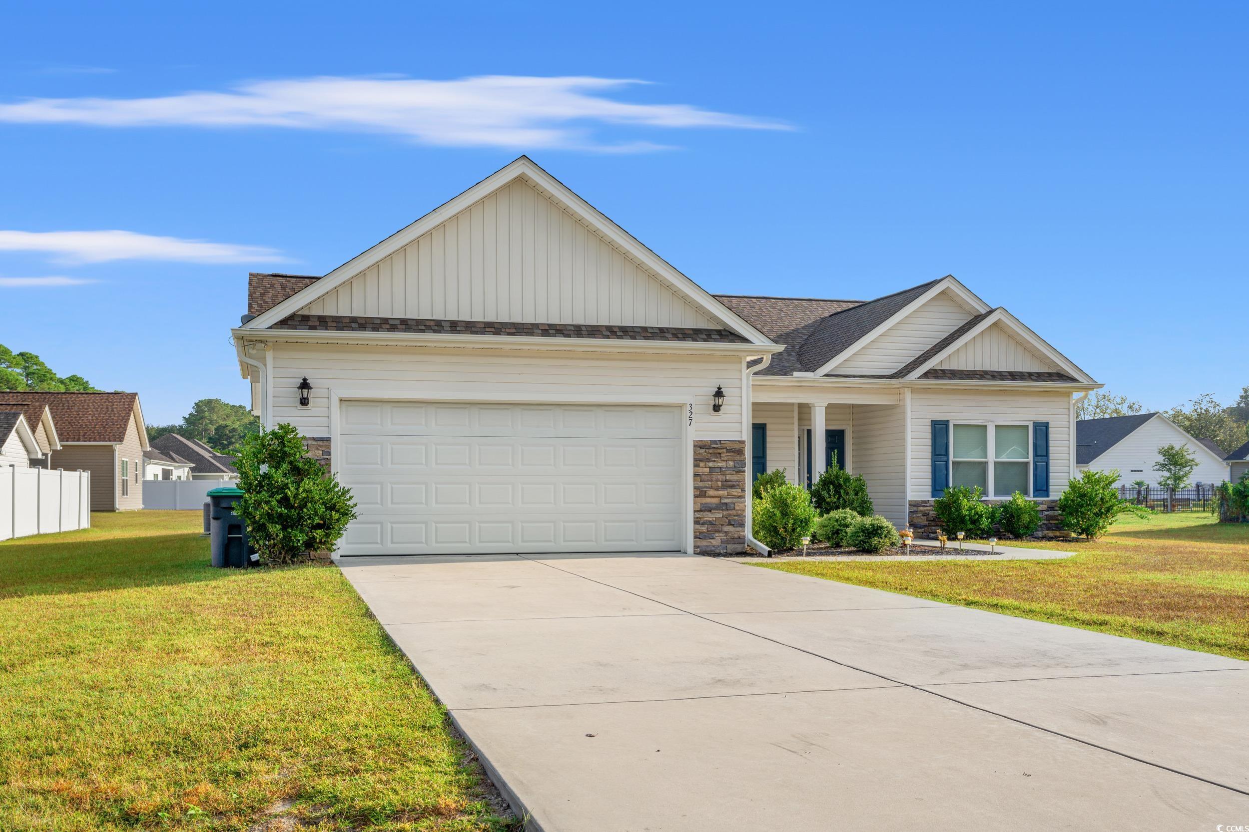View of front facade featuring stone siding, board and batten siding, driveway, and a porch