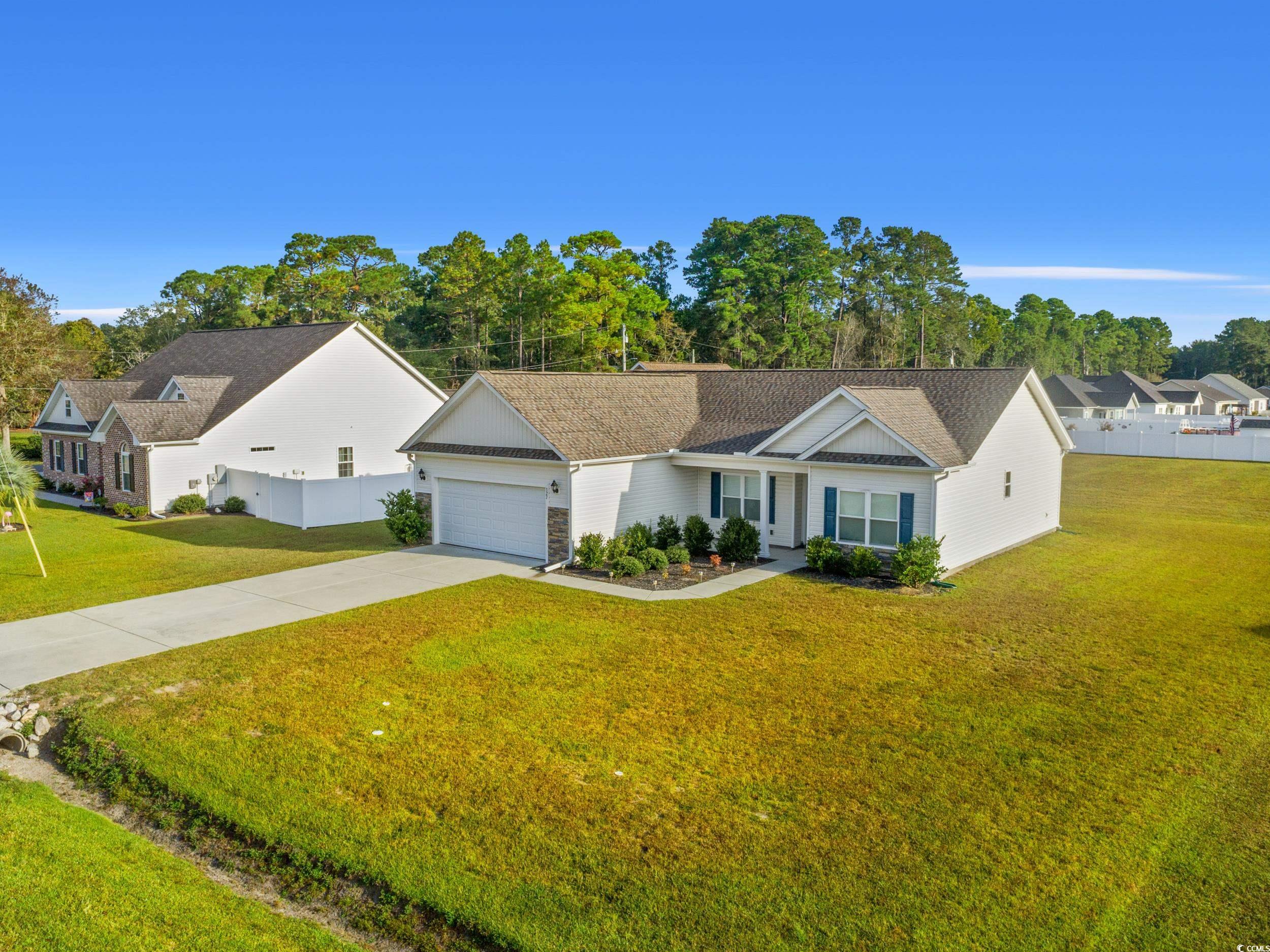 327 Fox Bay Road Loris, SC 29569 - Photo 20 of 23 Single story home featuring concrete driveway, an attached garage, roof with shingles, and view of wooded area