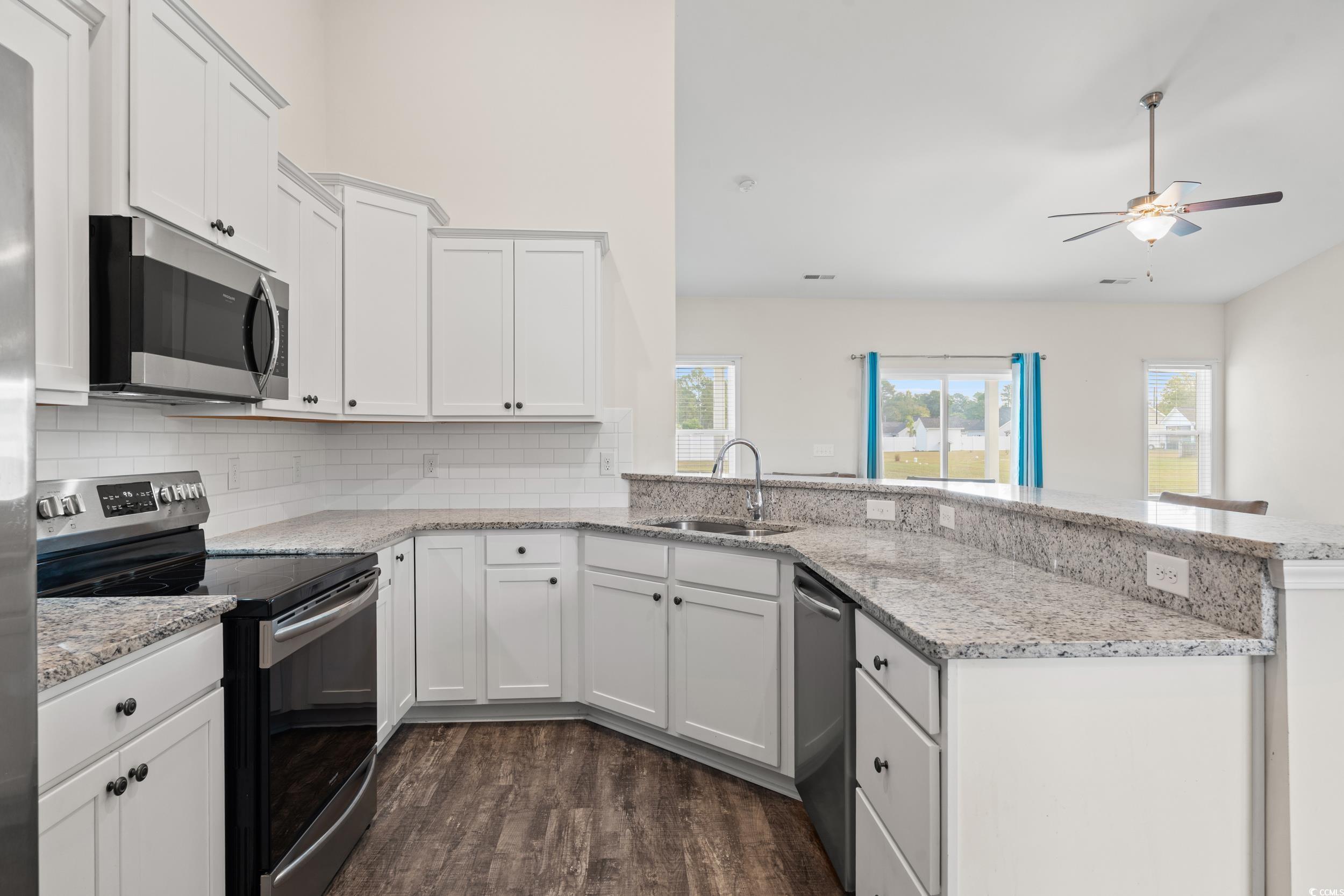 327 Fox Bay Road Loris, SC 29569 - Photo 8 of 23 Kitchen featuring stainless steel appliances, a peninsula, backsplash, white cabinets, and light stone counters