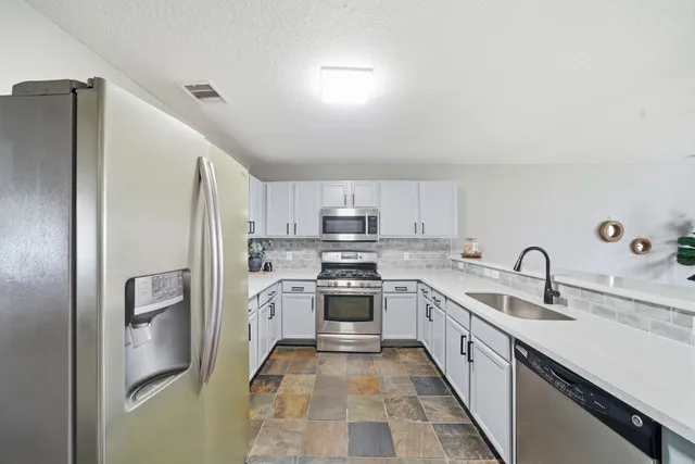 a kitchen with stainless steel appliances granite countertop a refrigerator and a sink