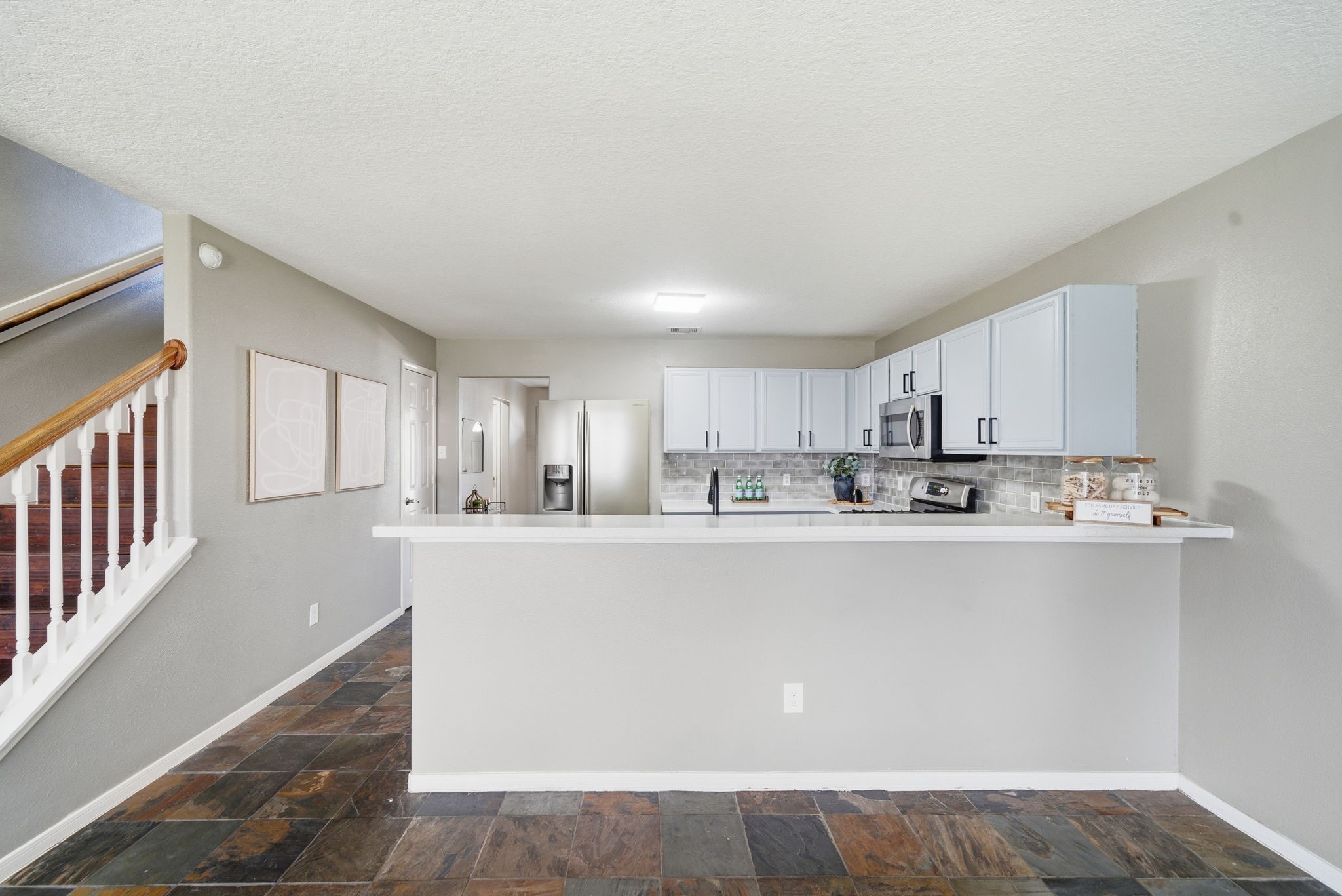 14422 Leafy Tree Drive Houston, TX 77090 - Photo 13 of 40 a large white kitchen with kitchen island a sink a stove a refrigerator and white cabinets
