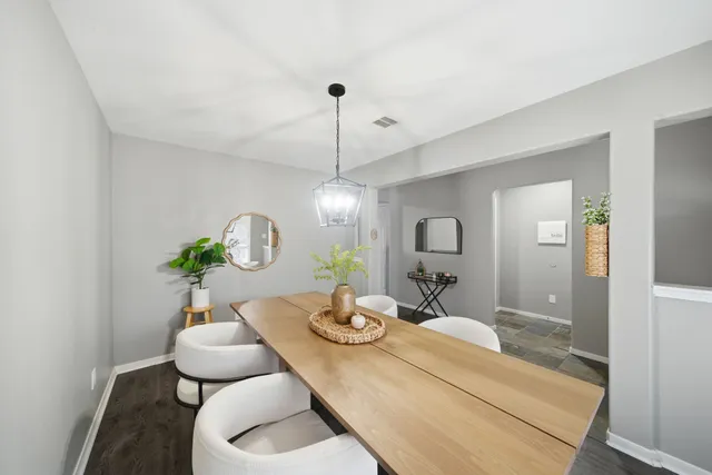 a dining room with wooden floor a chandelier a wooden table and chairs