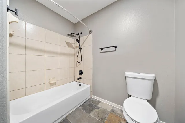 a white toilet sitting next to a bath tub and a shower