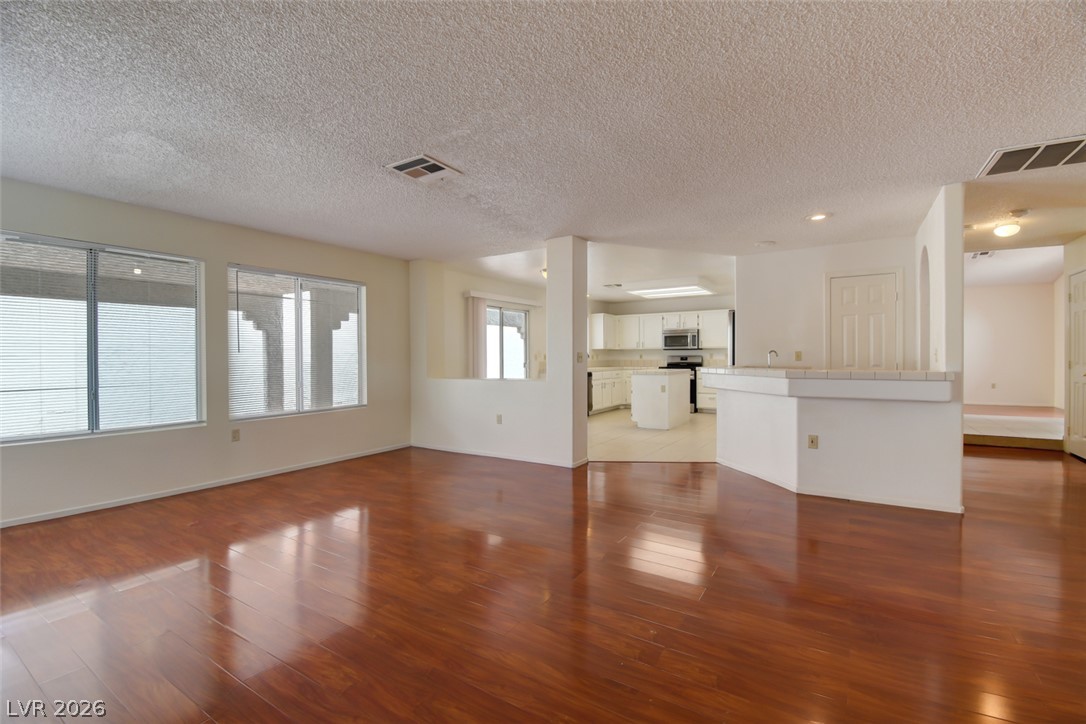 5 Tarryall Terrace Henderson, NV 89074 - Photo 17 of 44 Hardwood flooring extends throughout this luminous open-concept living area, flowing into a bright, white kitchen.