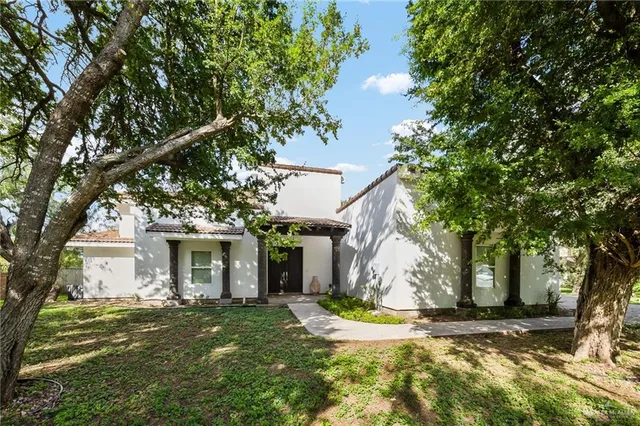 a view of a white house with a yard and large tree