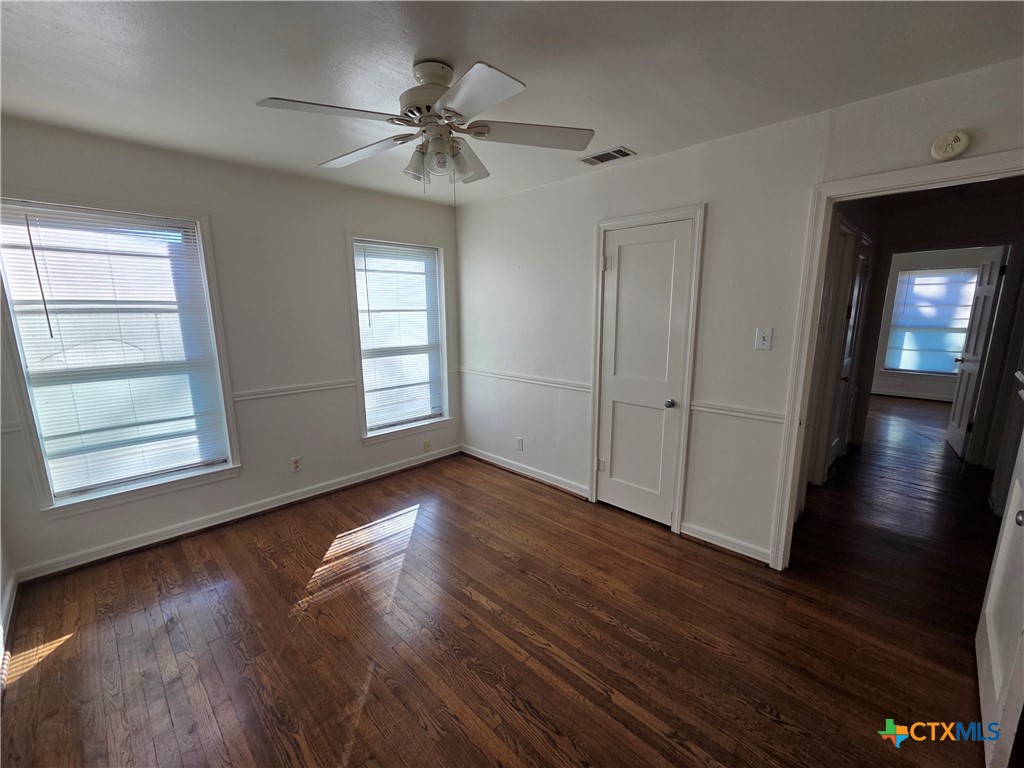 1506 South 9th Street Temple, TX 76504 - Photo 14 of 17 an empty room with wooden floor chandelier fan and windows