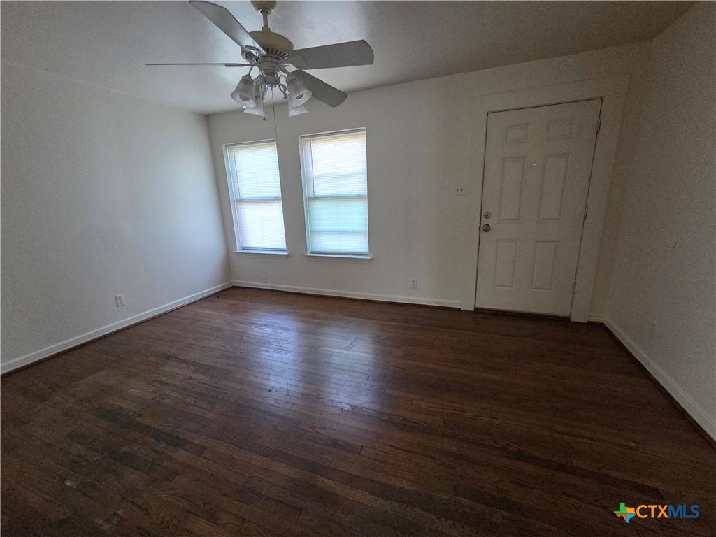 1506 South 9th Street Temple, TX 76504 - Photo 3 of 17 an empty room with wooden floor chandelier fan and windows