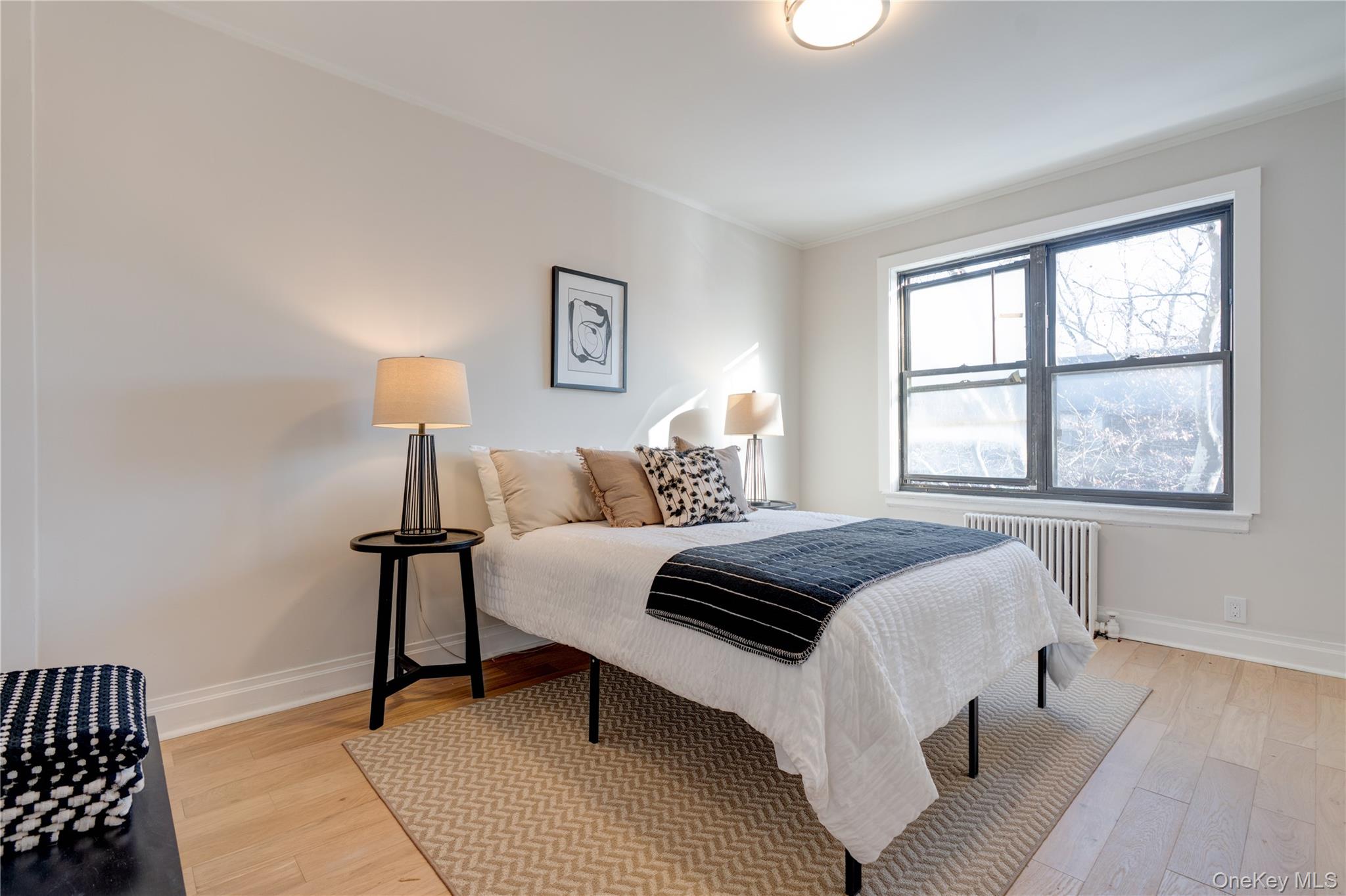 2226 76th Street, Unit C3 Queens, NY 11370 - Photo 16 of 20 a bedroom with a bed and a lamp with table