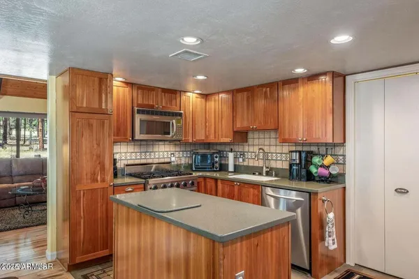 a kitchen with stainless steel appliances granite countertop refrigerator a sink a stove a microwave and island with wooden floor