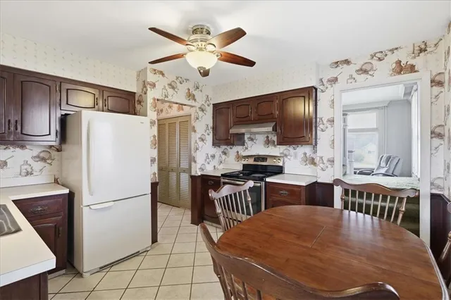 a kitchen with stainless steel appliances granite countertop a refrigerator a stove top oven a sink dishwasher and white cabinets with wooden floor