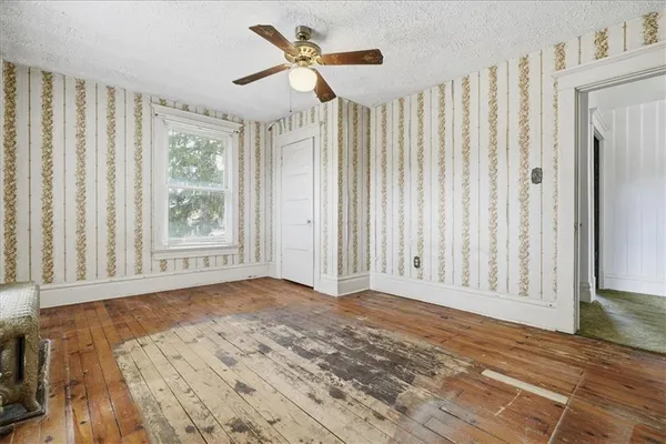 a view of an empty room with a window and wooden floor