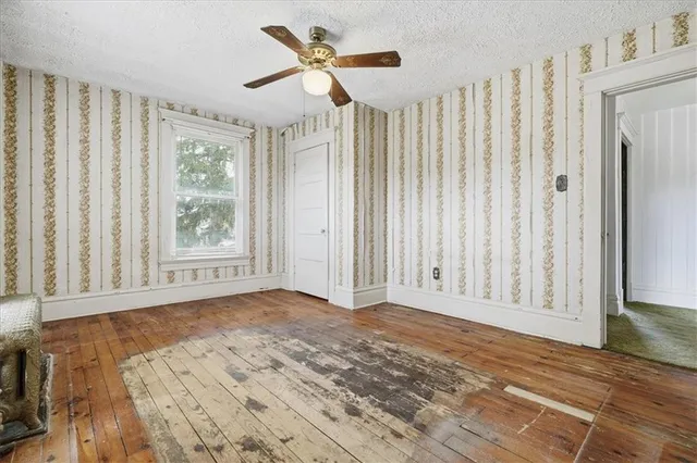 a view of an empty room with a window and wooden floor