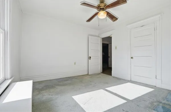 an empty room with closet and a chandelier fan