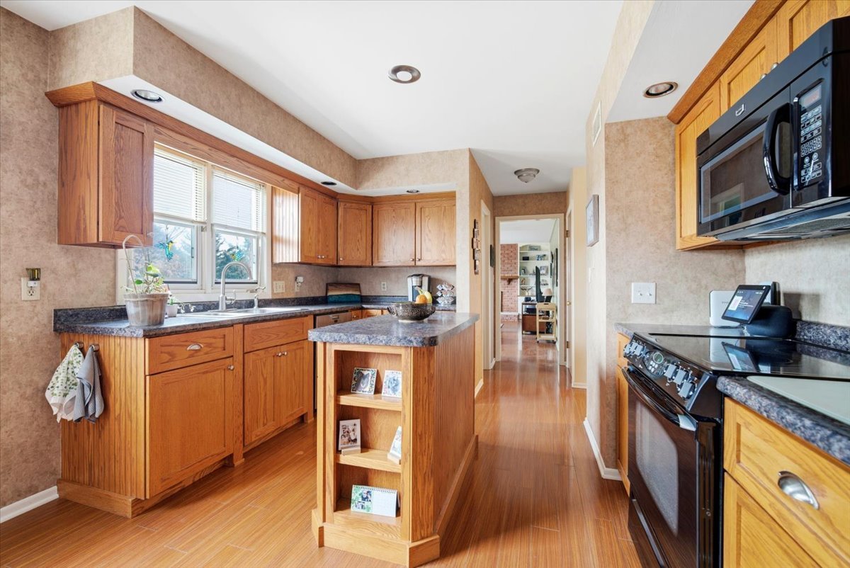 1204 Westview Drive Normal, IL 61761 - Photo 10 of 25 a kitchen with stainless steel appliances granite countertop a refrigerator a stove top oven a sink dishwasher and wooden cabinets with wooden floor