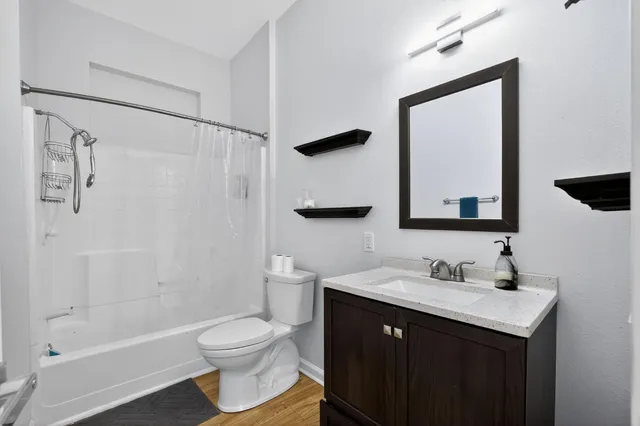 a bathroom with a toilet a sink a mirror a bathtub and shower