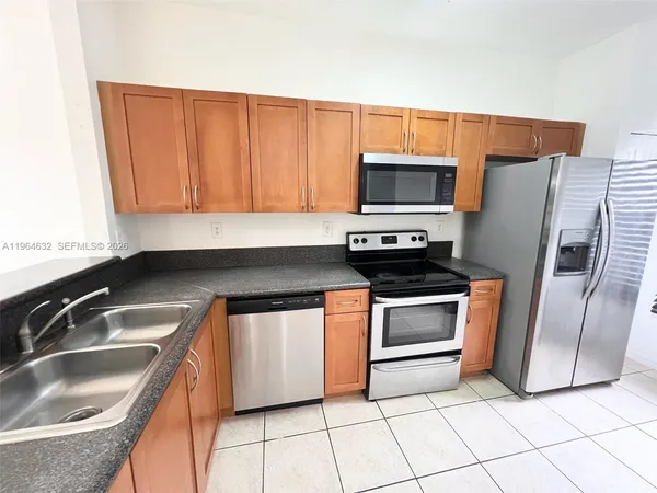 a kitchen with granite countertop a sink and a refrigerator