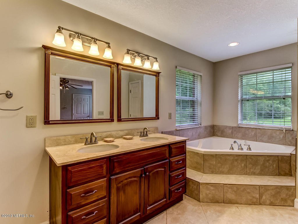 86051 Ellis Estates Landing Road Yulee, FL 32097 - Photo 15 of 35 a spacious bathroom with a tub double sink window and mirror