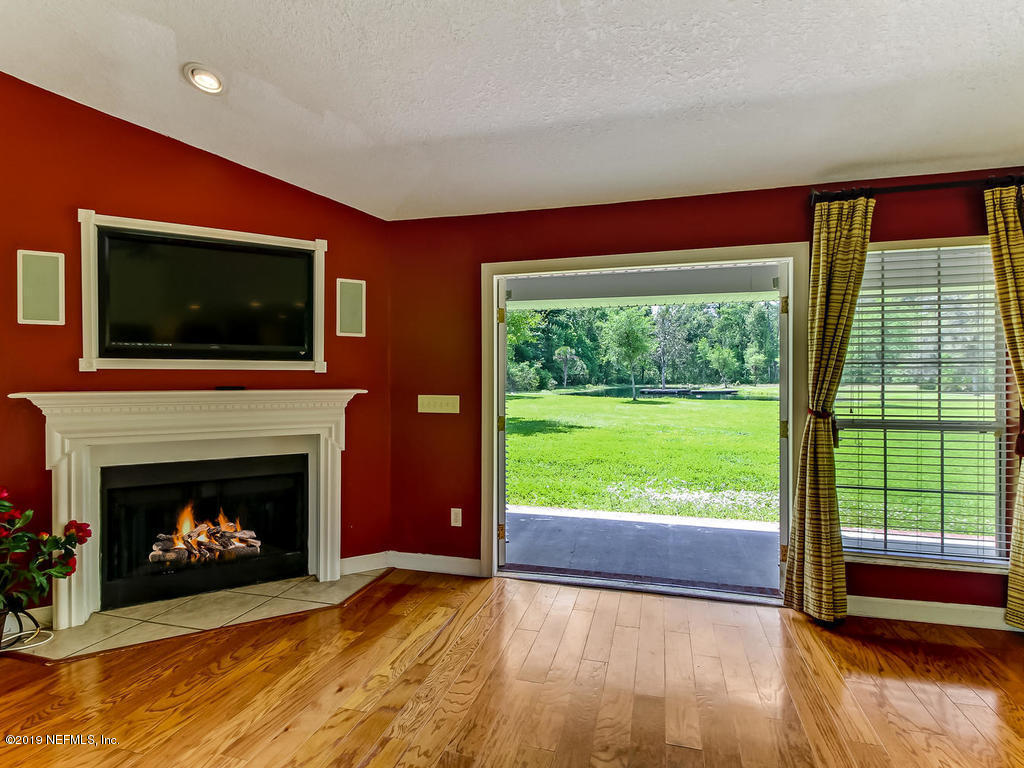 86051 Ellis Estates Landing Road Yulee, FL 32097 - Photo 2 of 35 a living room with a fireplace and a flat screen tv