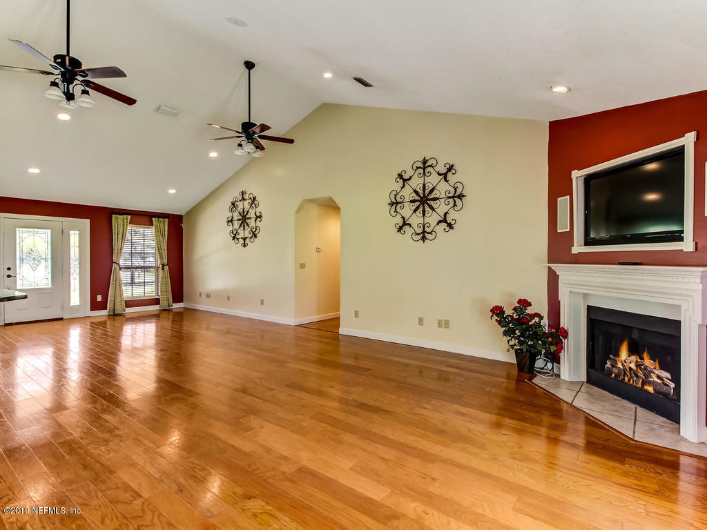 86051 Ellis Estates Landing Road Yulee, FL 32097 - Photo 5 of 35 an empty room with windows fireplace and a chandelier fan