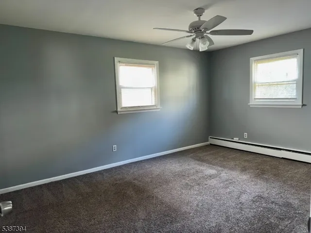 an empty room with windows and fan