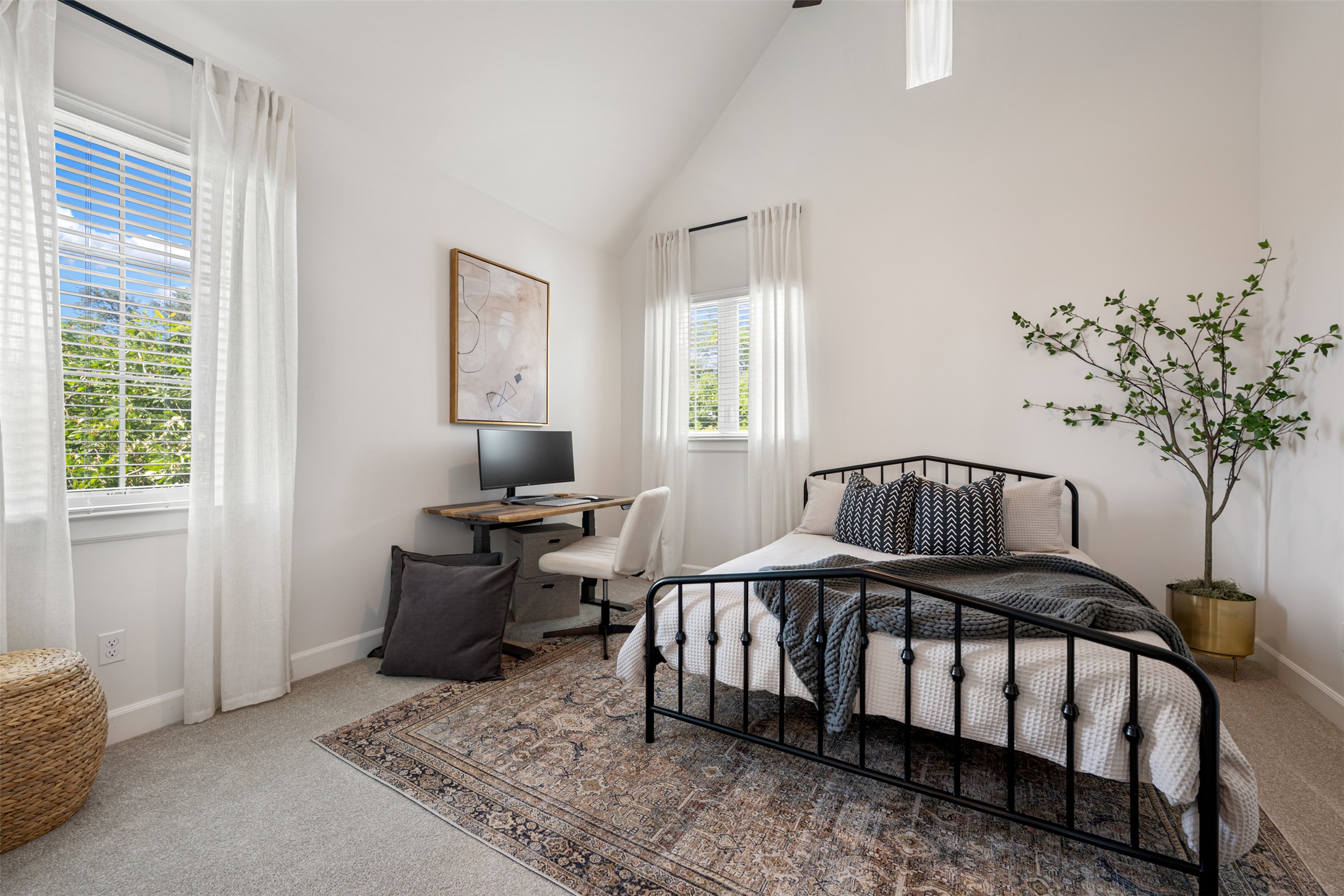 1301 West Street Georgetown, TX 78626 - Photo 33 of 40 An inviting bedroom with vaulted ceilings, featuring a dedicated workspace and naturally illuminated by two large windows.
