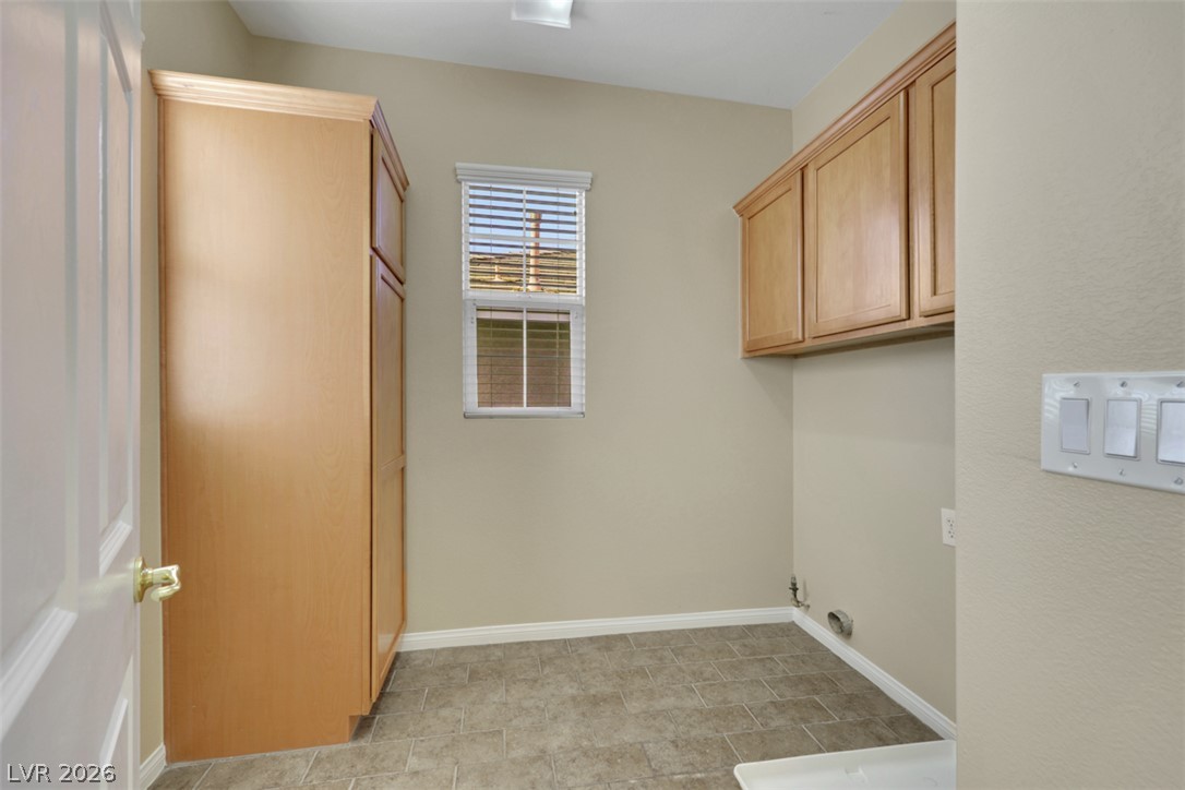 10328 Hawk Ravine Street Las Vegas, NV 89178 - Photo 27 of 55 Functional laundry space featuring ample cabinetry and durable tile flooring for everyday convenience.