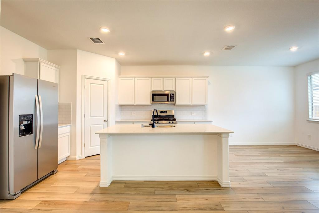 532 Ranchito Pass Haslet, TX 76052 - Photo 12 of 38 a view of a kitchen with kitchen island a sink wooden floor and a refrigerator