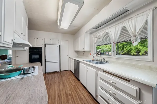 a kitchen with stainless steel appliances a sink a stove a refrigerator cabinets and a large window