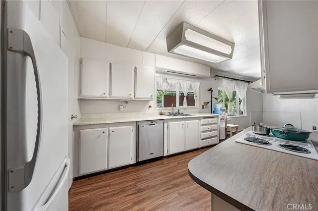 a kitchen with white cabinets and wooden floor