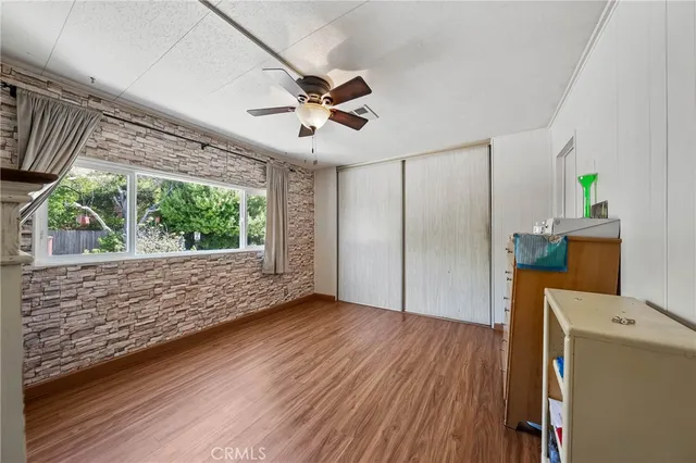 a view of empty room with wooden floor and fan