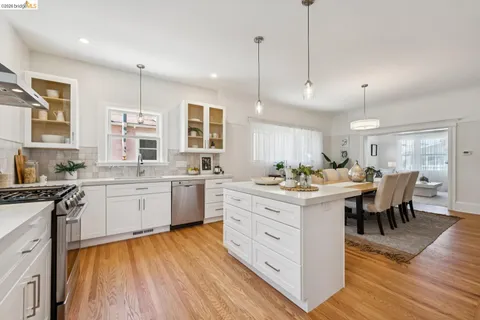 a large kitchen with white cabinets and wooden floor