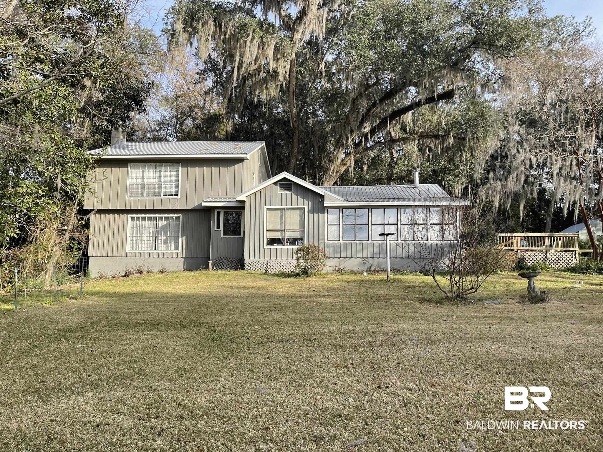 6621 Purvis Road Daphne, AL 36527 - Photo 48 of 59 Rear view of property with a lawn, a metal roof, view of wooded area, and a chimney