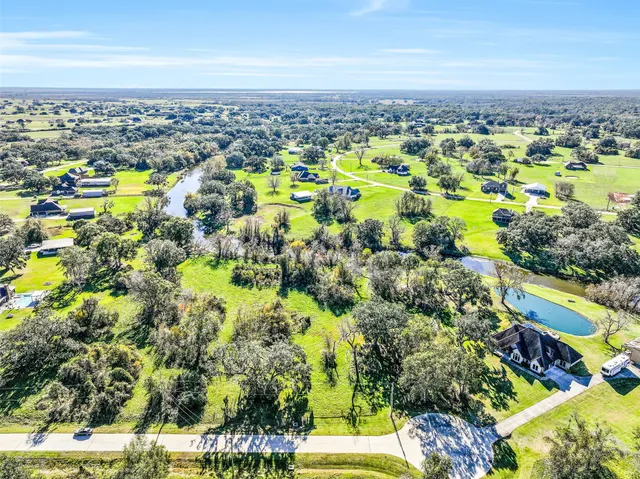 an aerial view of a residential houses with outdoor space and trees