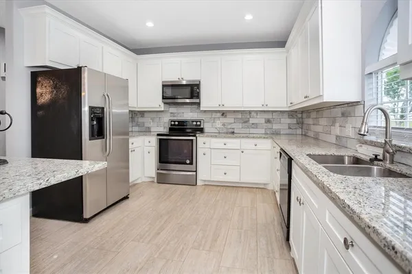 a kitchen with stainless steel appliances granite countertop a sink stove refrigerator and cabinets