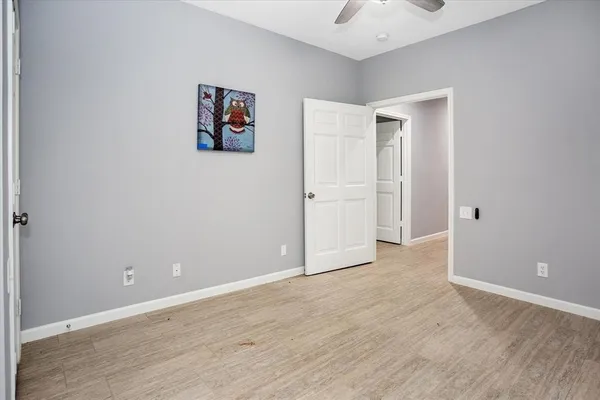 an empty room with wooden floor and ceiling fan