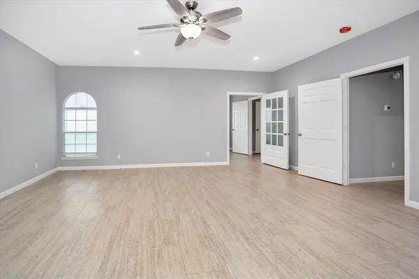 an empty room with wooden floor closet and windows
