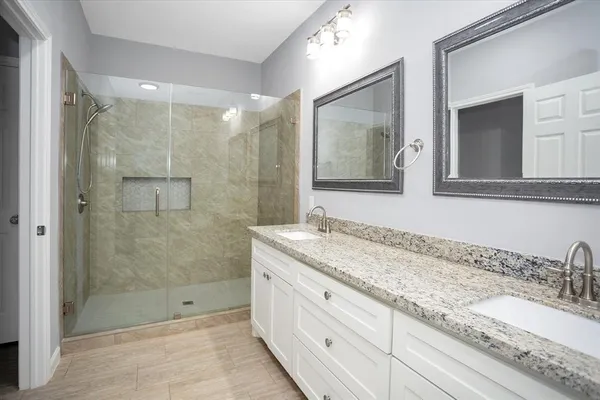 a bathroom with a granite countertop sink mirror shower and