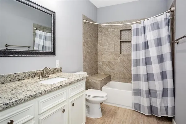 a bathroom with a granite countertop sink a toilet and a shower