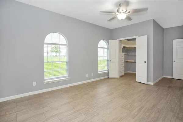 an empty room with windows closet and chandelier fan