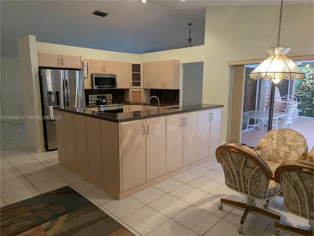 a kitchen with stainless steel appliances kitchen island granite countertop a refrigerator and a stove top oven