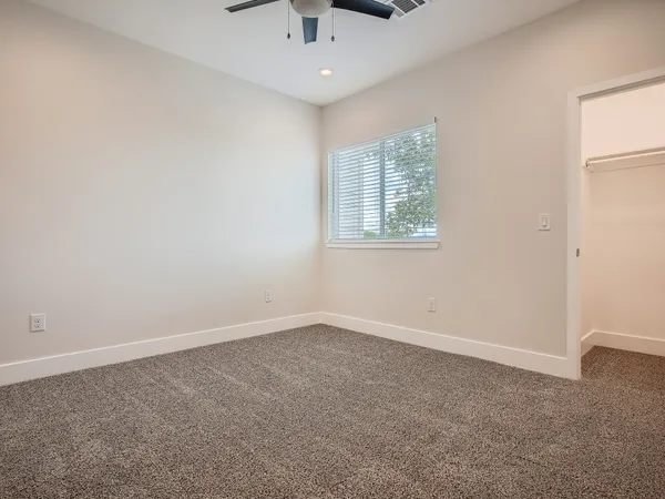 an empty room with windows and chandelier fan